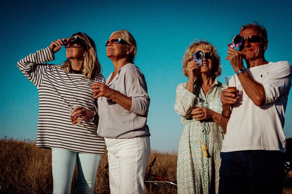 People watching a partial solar eclipse through eclipse glasses